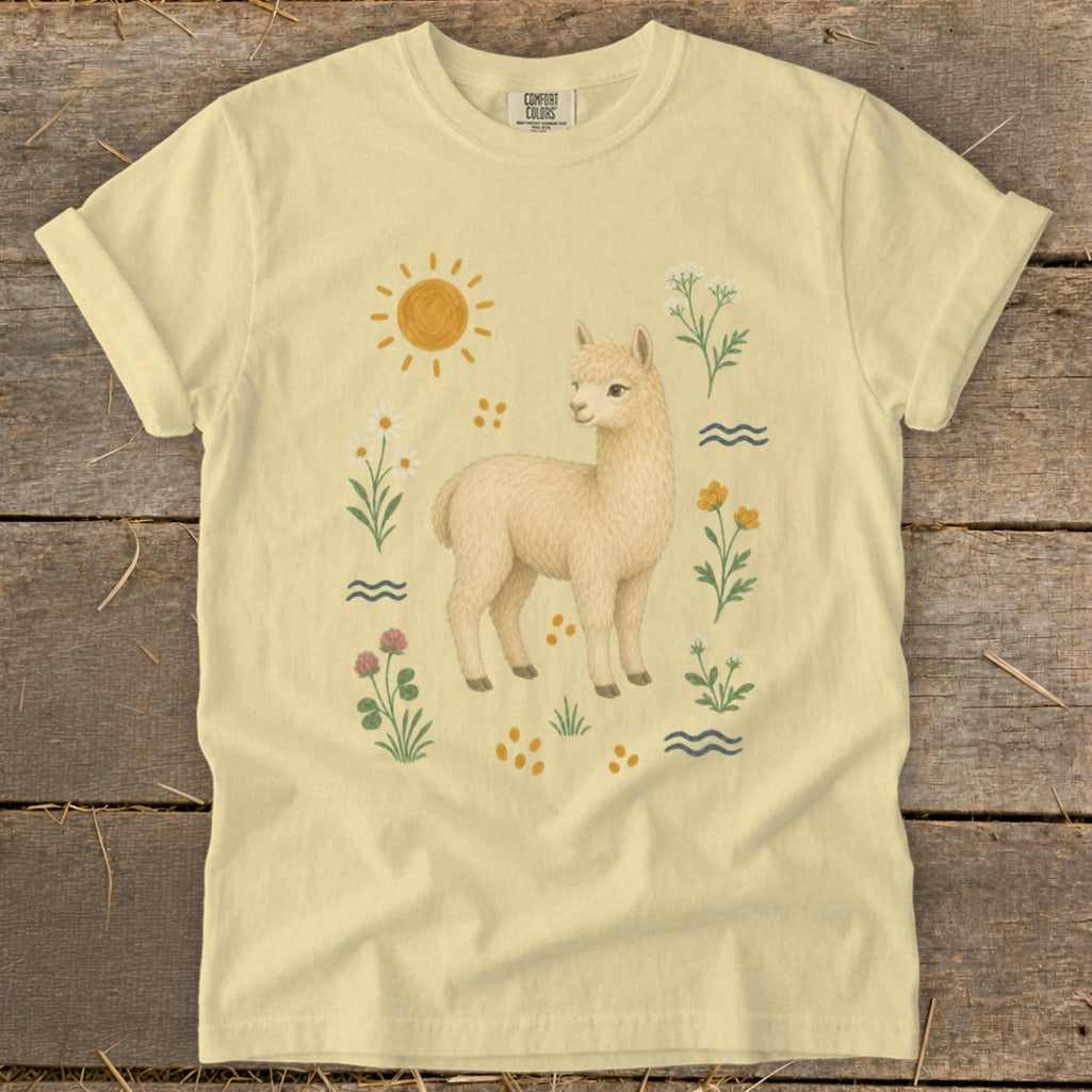 Cream t-shirt with a whimsical alpaca and nature illustration, featuring a sun and wildflowers.