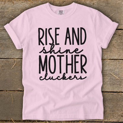 Pink t-shirt with black text "RISE AND shine MOTHER cluckers".
