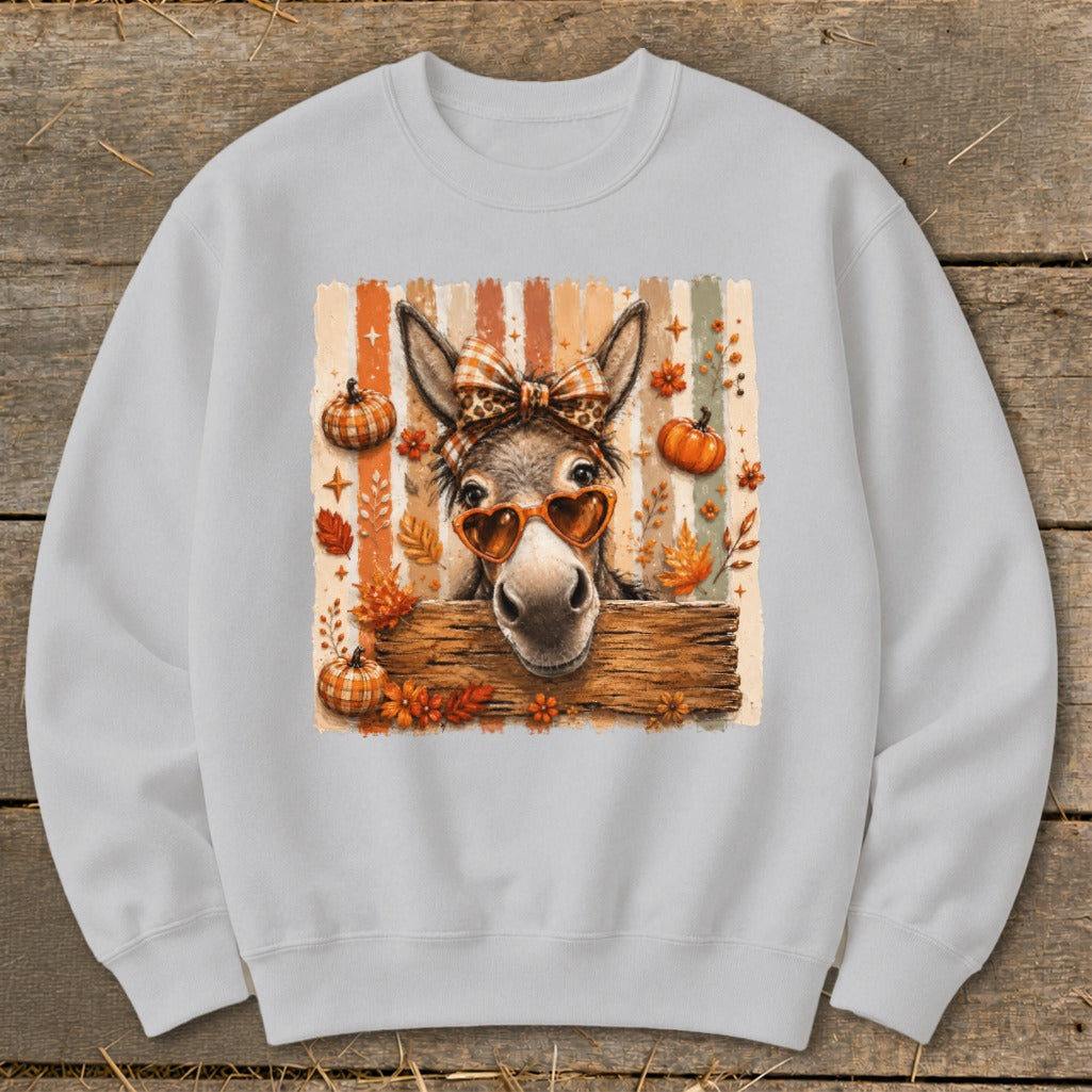 Donkey wearing heart sunglasses and plaid bow, with pumpkins and fall leaves.