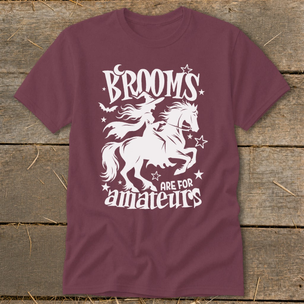 Maroon t-shirt with white graphic of witch on horseback and text "BROOMS ARE FOR AMATEURS".