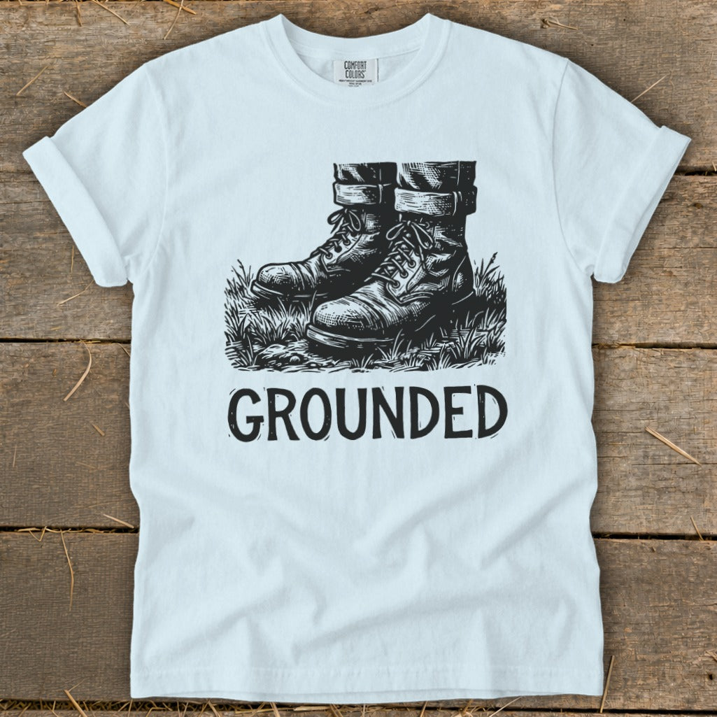 White t-shirt with black graphic of boots in grass and the word GROUNDED.