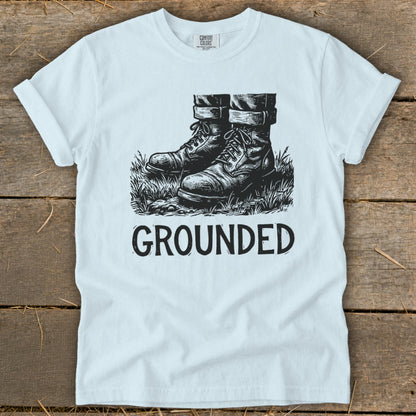 White t-shirt with black graphic of boots in grass and the word GROUNDED.