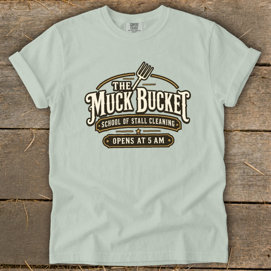 Light blue t-shirt with "The Muck Bucket School of Stall Cleaning Opens at 5 AM" graphic.