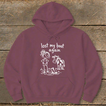 Maroon hoodie featuring a graphic of a frustrated stick-figure girl standing in mud next to a cow, with the text "lost my boot again."