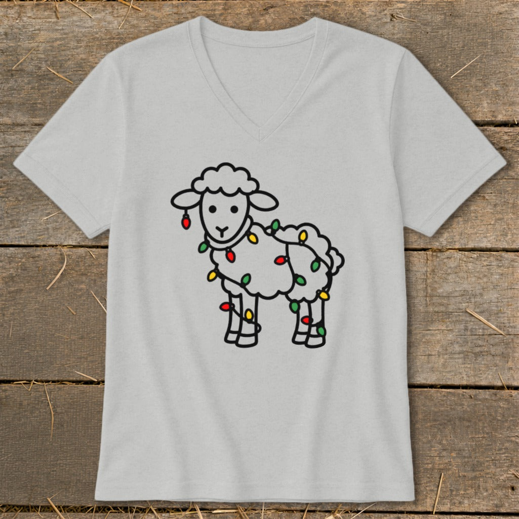 Light gray V-neck t-shirt featuring a cartoon sheep wrapped in colorful Christmas lights, displayed on wood.