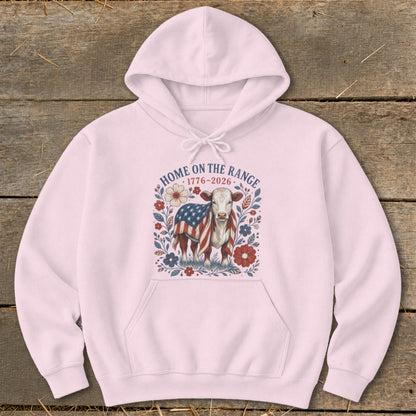 Pink hoodie with a cow wrapped in an American flag and "Home on the Range 1776-2026" text.