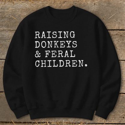 Black sweatshirt with white text: "RAISING DONKEYS & FERAL CHILDREN."