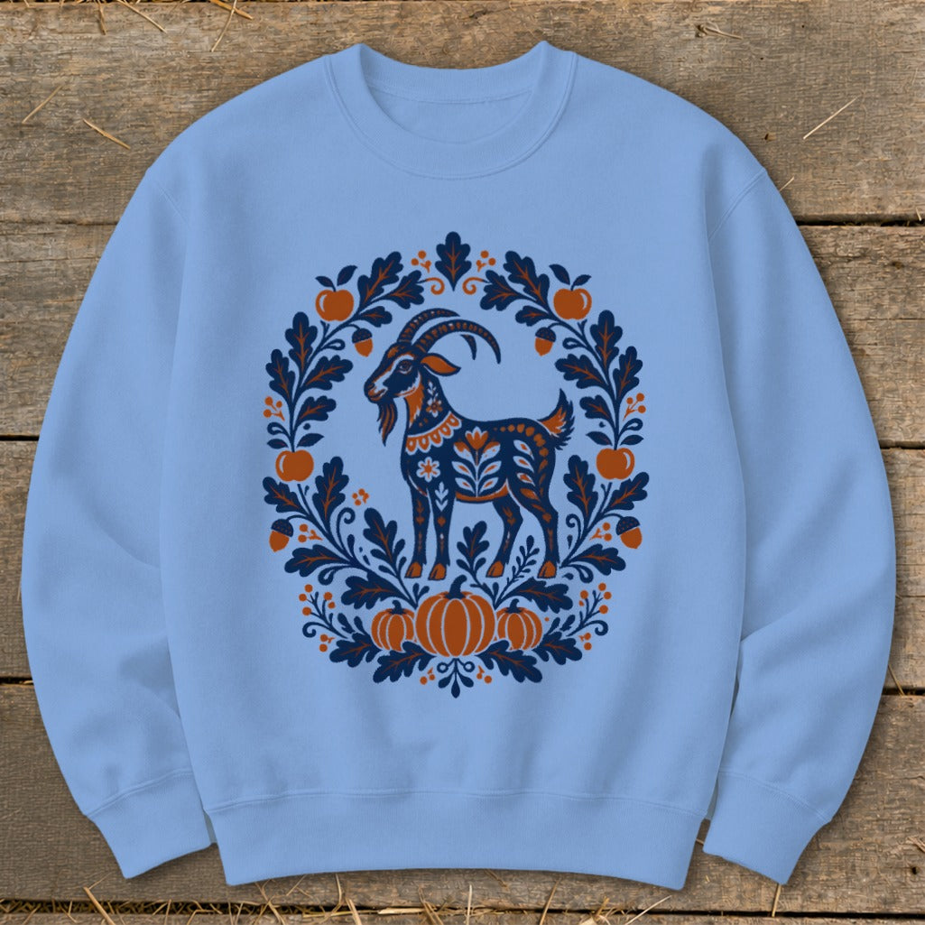 Light blue crewneck sweatshirt featuring a blue and orange folkloric goat and pumpkin wreath design.