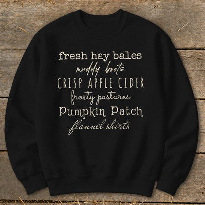 Black sweatshirt with white text listing fall activities: fresh hay bales, muddy boots, crisp apple cider, frosty pastures, pumpkin patch, flannel shirts.