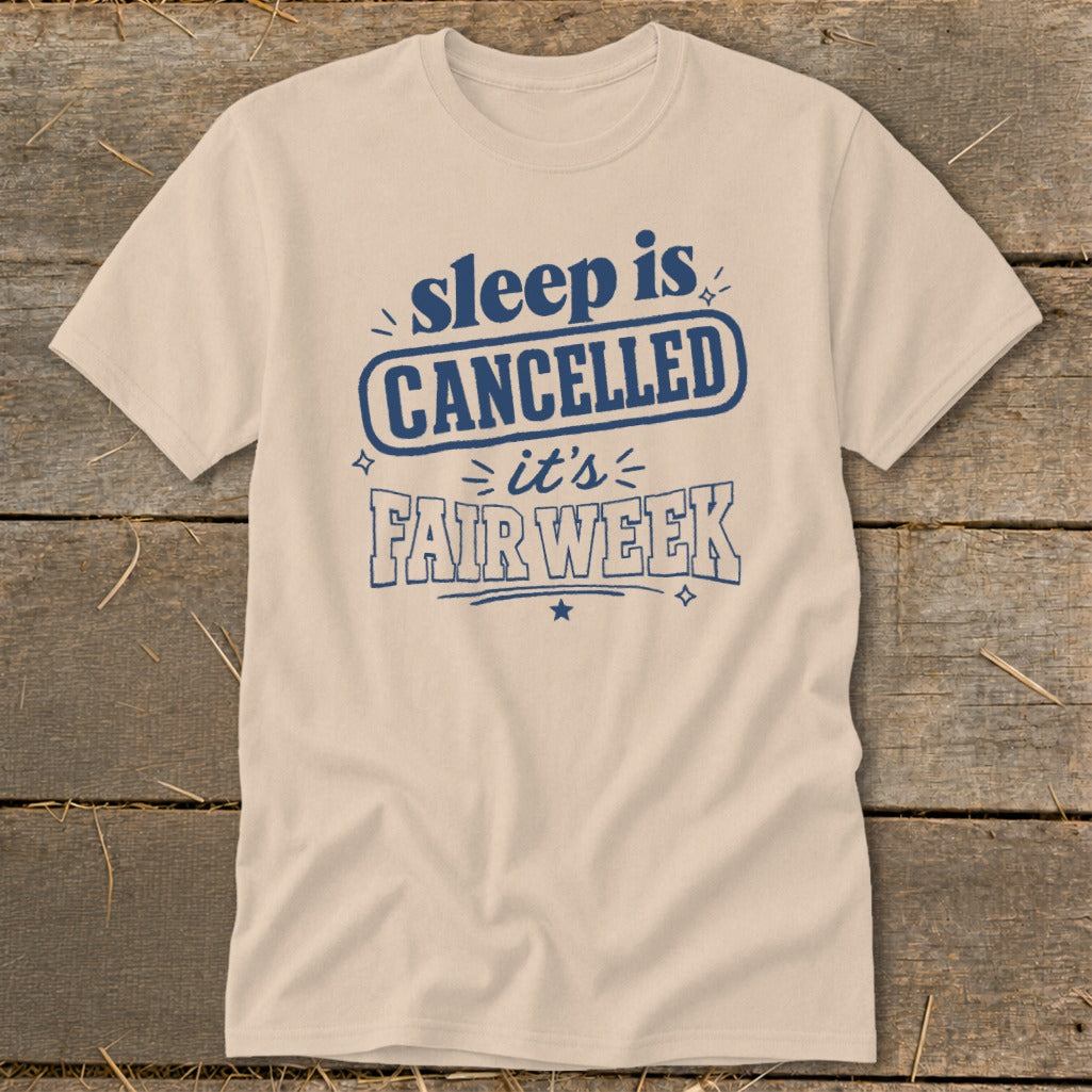 Beige t-shirt with blue text "sleep is CANCELLED = it's FAIR WEEK"