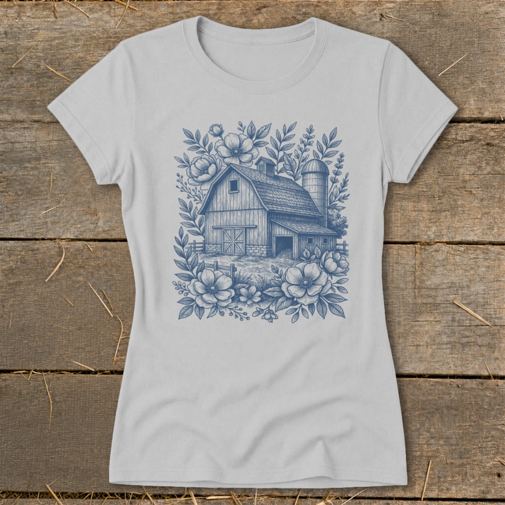 Light grey t-shirt with a blue line drawing of a barn and silo surrounded by flowers.