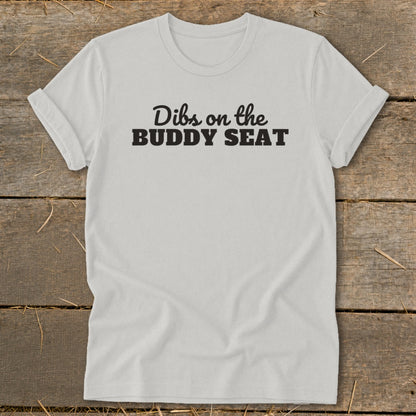White t-shirt with black text "Dibs on the BUDDY SEAT".
