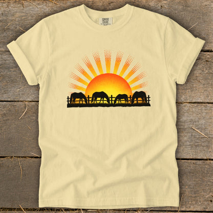 Light yellow t-shirt with horses grazing at sunrise graphic.
