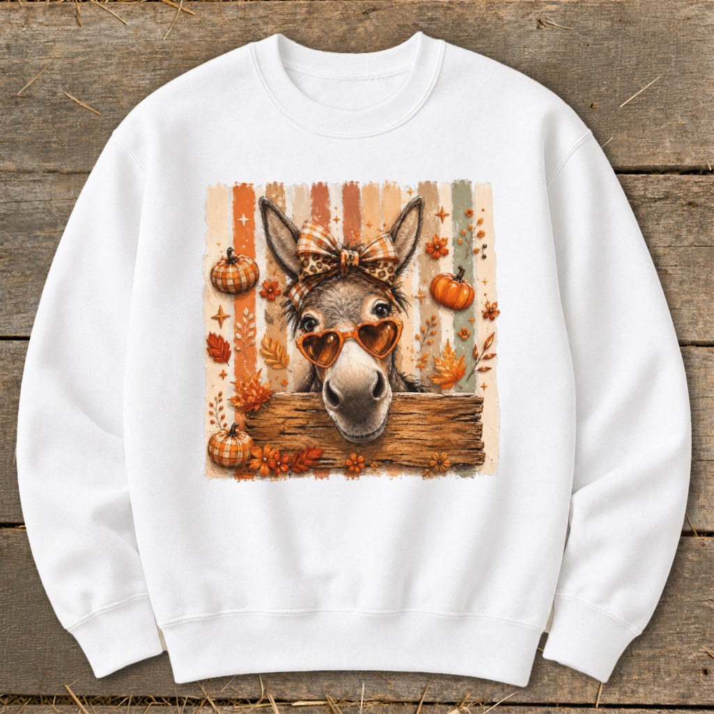 Donkey wearing a bow and heart sunglasses with pumpkins and fall leaves.
