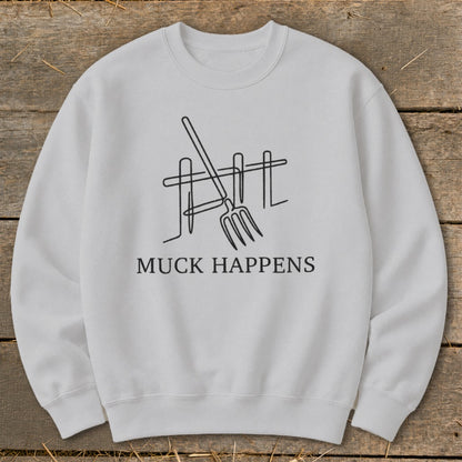 White sweatshirt with "MUCK HAPPENS" text and line art of a pitchfork and fence.