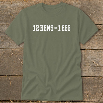 An olive green crewneck t-shirt with the white distressed text 12 HENS = 1 EGG printed on the chest, laid flat on a rustic wooden surface.