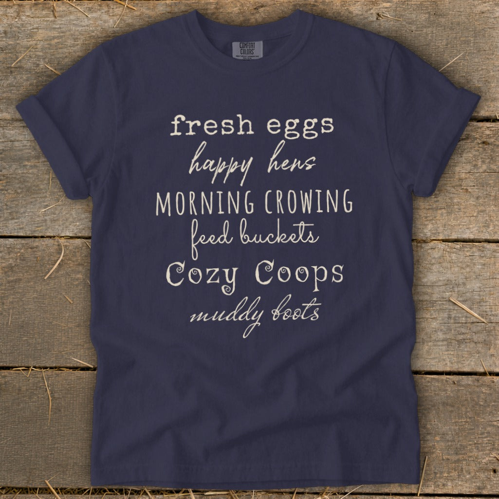 Navy t-shirt with text "fresh eggs happy hens Morning Crowing feed buckets Cozy Coops muddy boots"