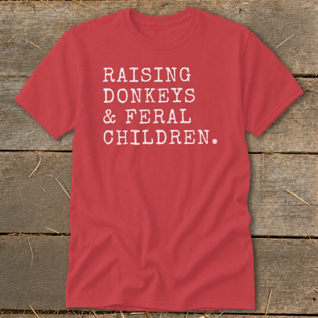 Red t-shirt with white text reading "RAISING DONKEYS & FERAL CHILDREN."