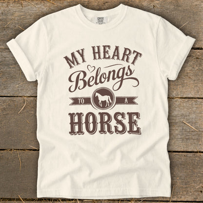 White t-shirt with brown text "My Heart Belongs To A Horse" and horse silhouette.