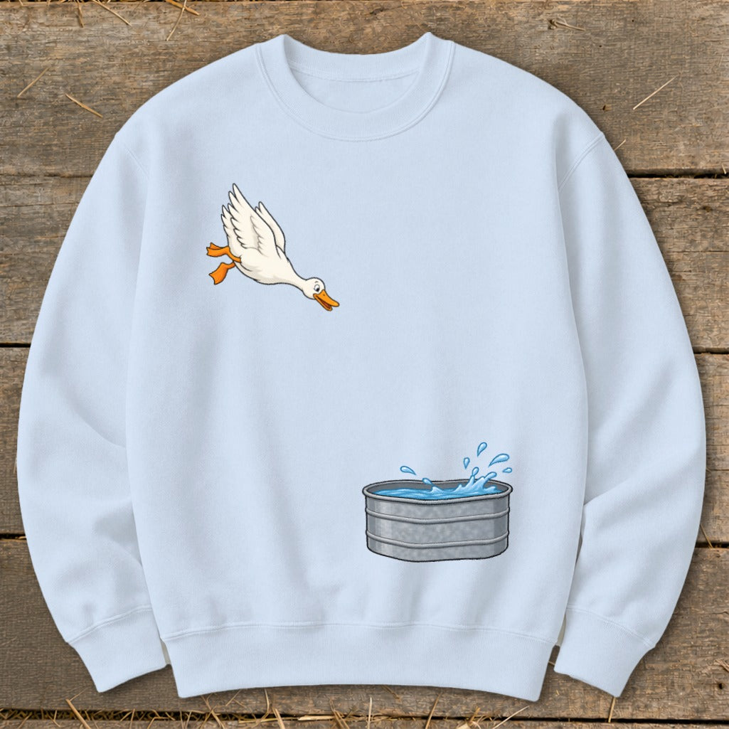Light blue sweatshirt with a graphic of a duck flying towards a galvanized tub of water.
