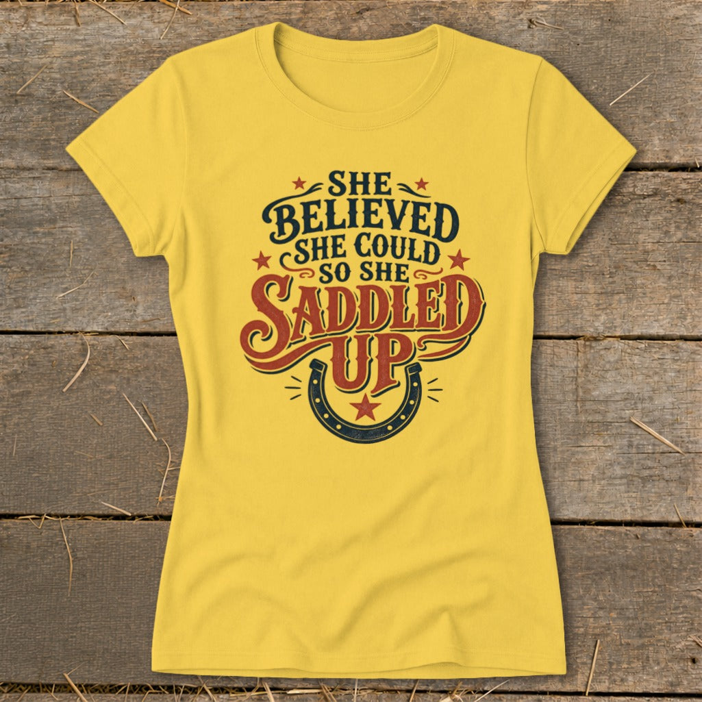 Yellow t-shirt with "She believed she could so she saddled up" text and horseshoe.