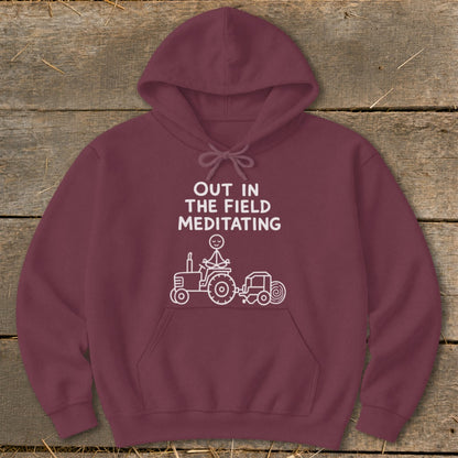Maroon hoodie with text "OUT IN THE FIELD MEDITATING" and a stick figure on a tractor.