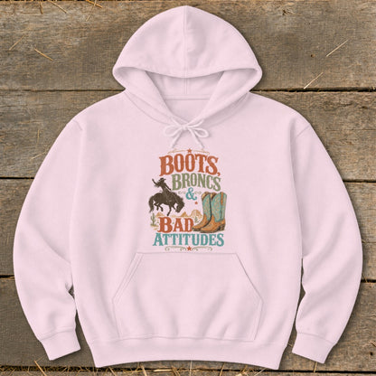 Pink hoodie with "Boots Broncs & Bad Attitudes" graphic including cowboy and boots.