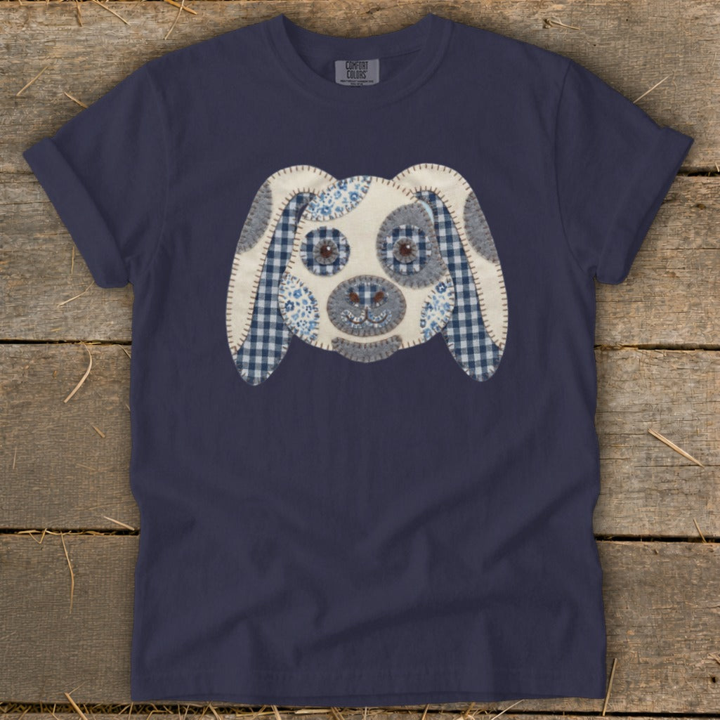 Navy blue t-shirt with a stitched applique dog face in blue and white patterns.