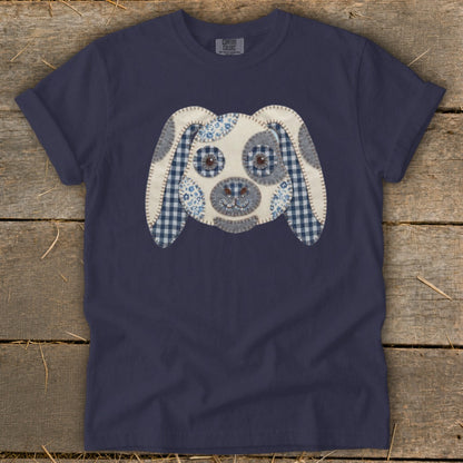 Navy blue t-shirt with a stitched applique dog face in blue and white patterns.
