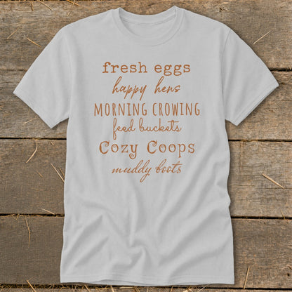 Light gray t-shirt with "fresh eggs happy hens MORNING CROWING feed buckets Cozy Coops muddy boots" text.