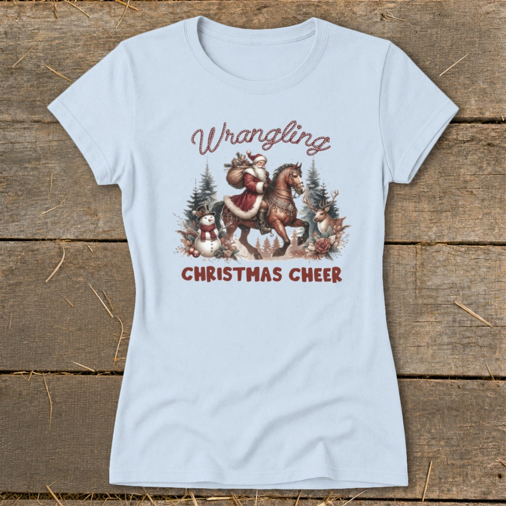 Light blue t-shirt with a graphic of Santa riding a horse, with "Wrangling Christmas Cheer" text.