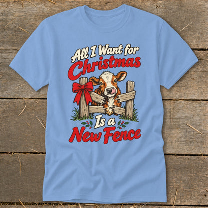 Light blue t-shirt with a cow peeking over a fence with text "All I Want for Christmas Is a New Fence".