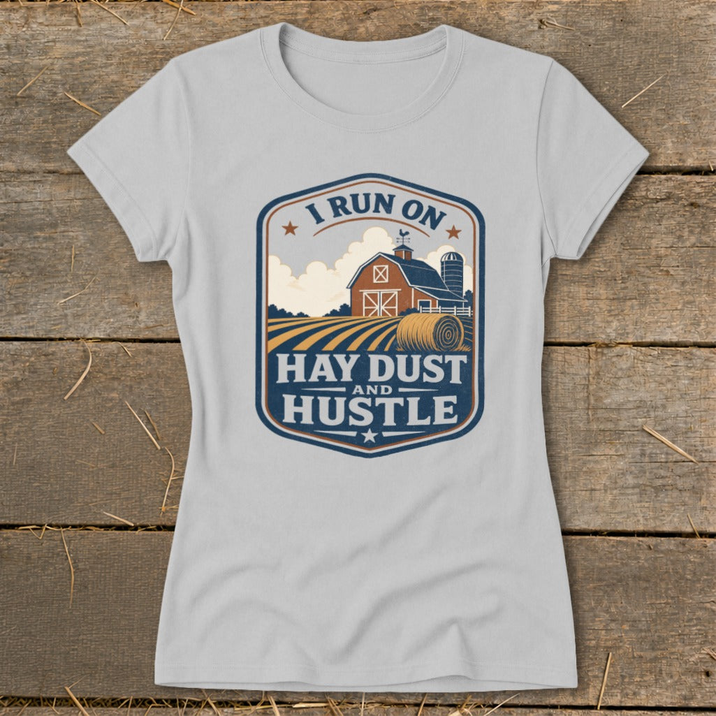 T-shirt graphic with barn, hay bale, and "I run on hay dust and hustle" text.