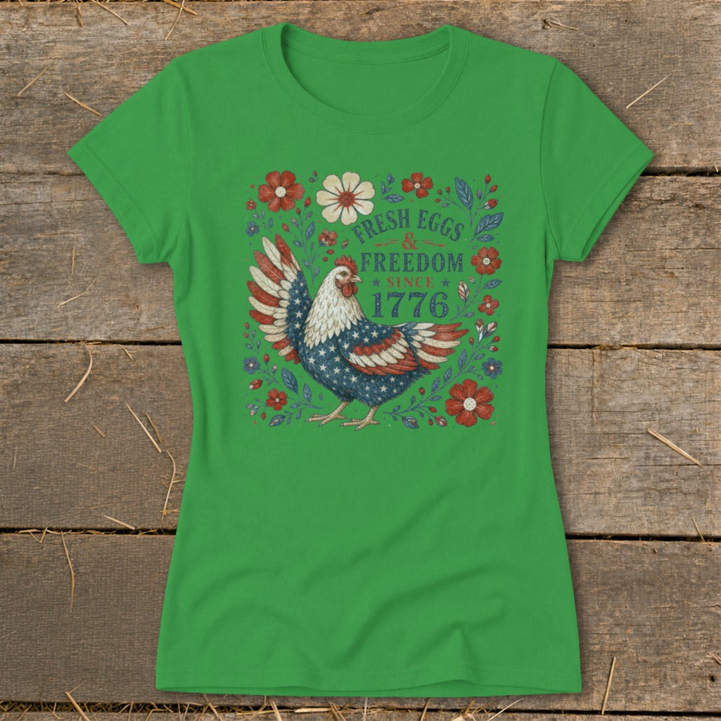 Green t-shirt with a chicken design featuring American flag wings and text "Fresh Eggs & Freedom Since 1776".