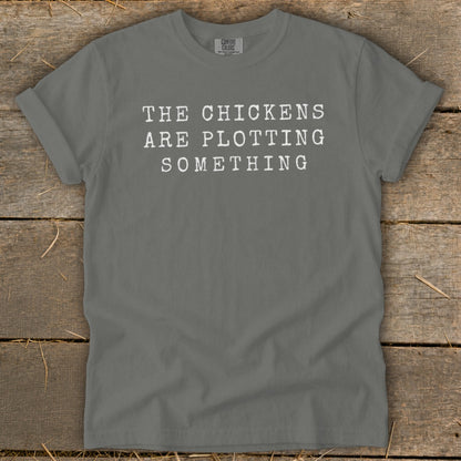 Gray t-shirt with white text reading "THE CHICKENS ARE PLOTTING SOMETHING."