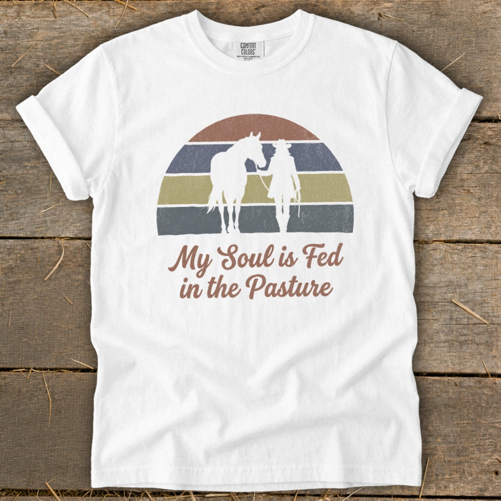White t-shirt with graphic of horse and person and text "My Soul is Fed in the Pasture".