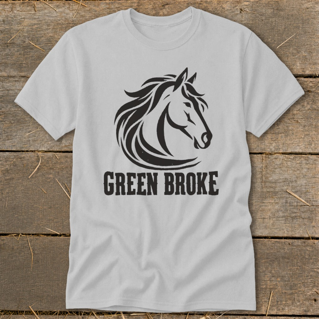 A light grey t-shirt featuring a black graphic of a horse head and the text GREEN BROKE on a wooden background.