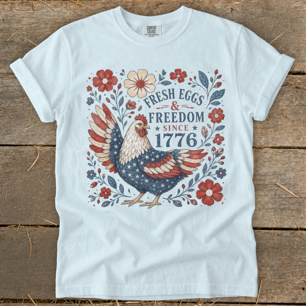 White t-shirt with patriotic chicken and "Fresh Eggs & Freedom Since 1776" text.
