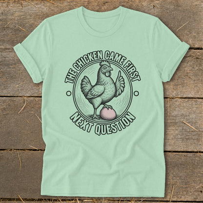 Mint t-shirt with chicken and egg graphic and text "The chicken came first. Next question."
