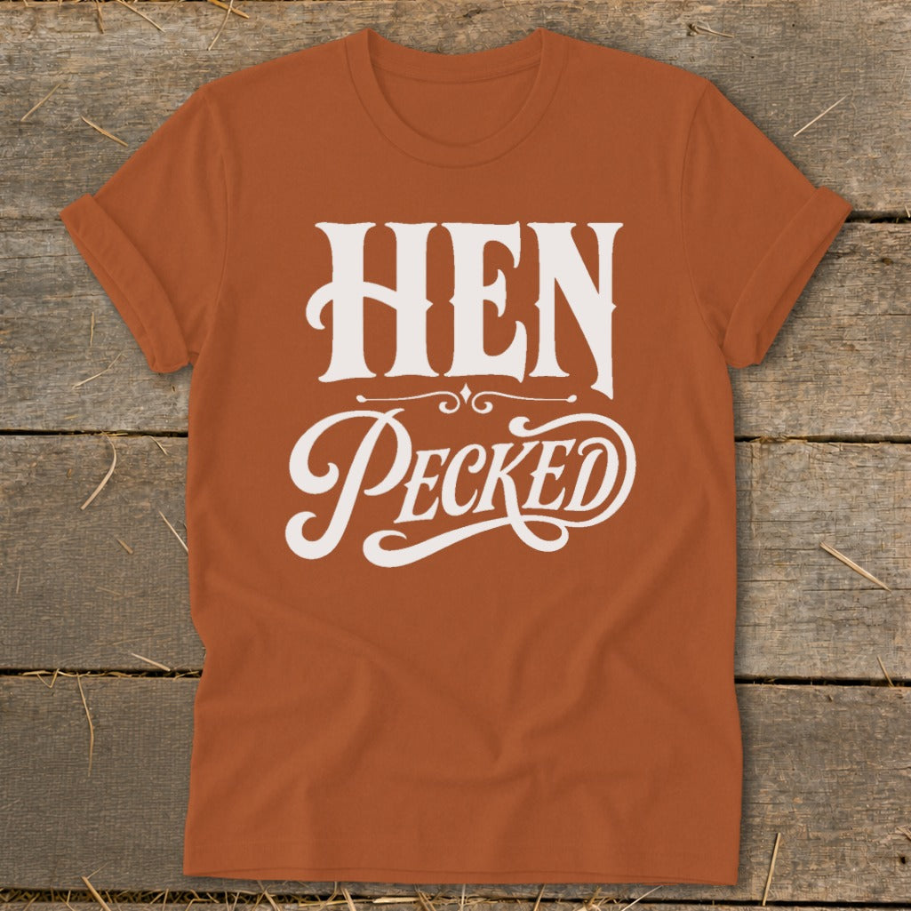 Orange t-shirt with white text reading "HEN Pecked" in decorative fonts.