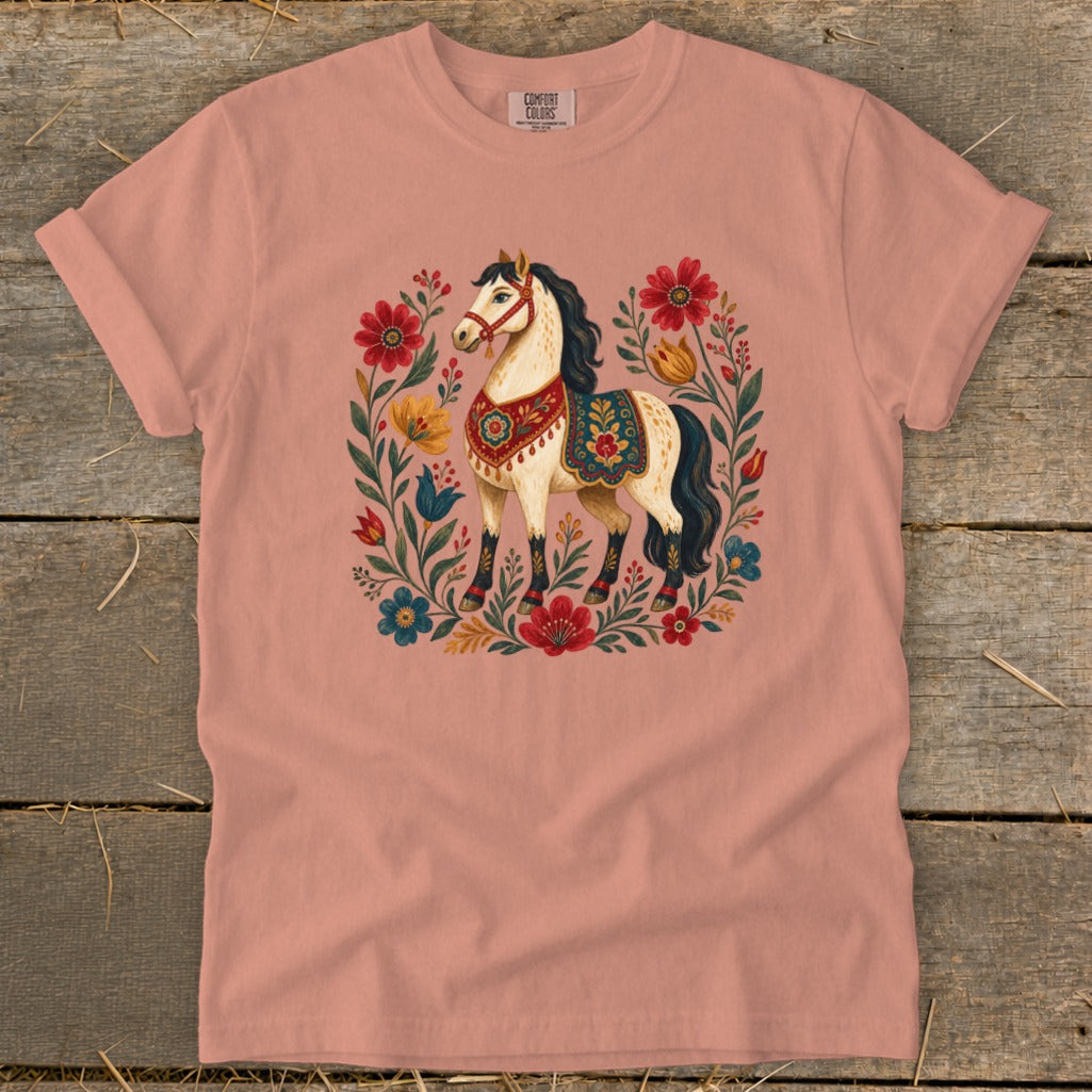 Peach t-shirt with a cream horse surrounded by floral art and foliage.