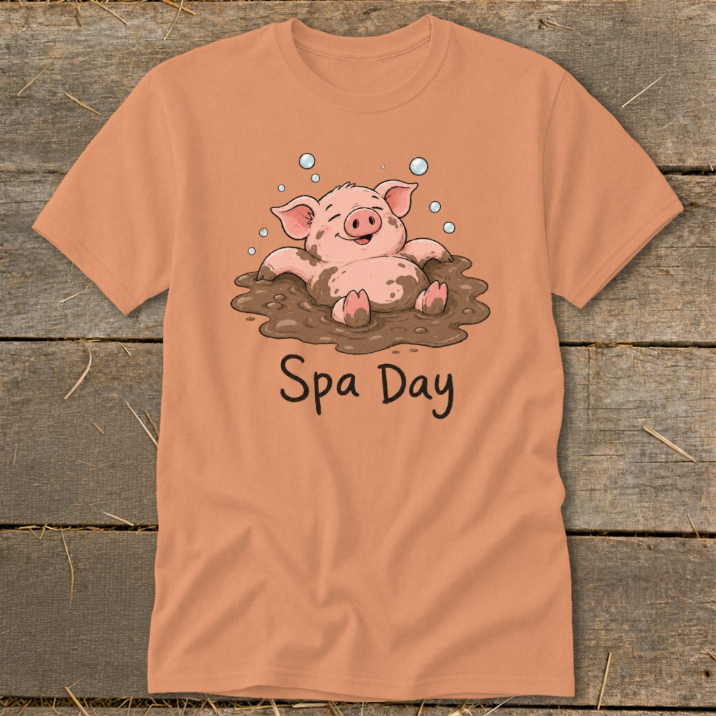 Peach t-shirt with illustration of a happy pig enjoying a mud bath, text "Spa Day".
