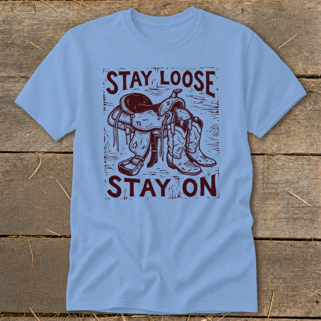 Light blue t-shirt with western saddle and boots graphic and text "Stay Loose Stay On".
