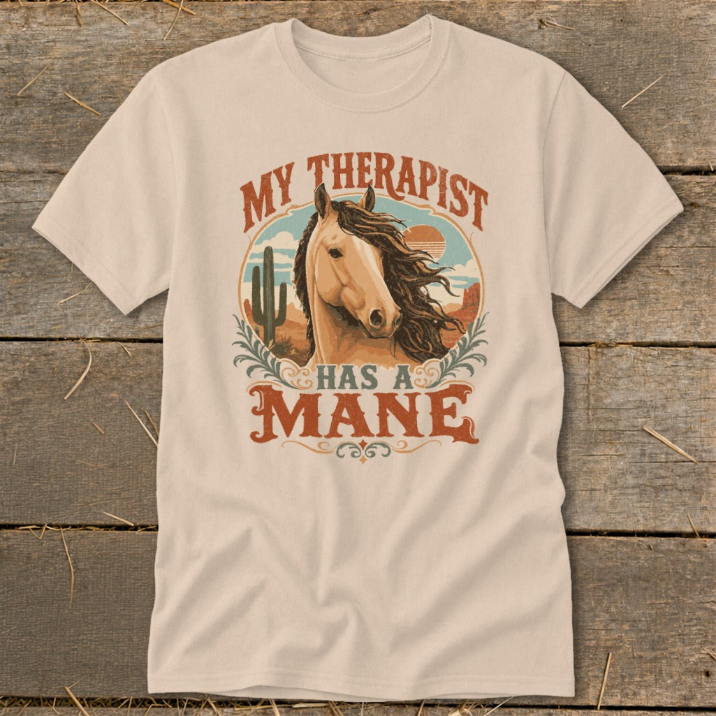 Cream t-shirt with "My Therapist Has A Mane" and horse in desert scene graphic.