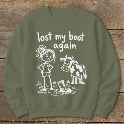 Olive green crewneck sweatshirt featuring a white graphic of a sad stick figure, a cow, and a lost boot in mud with the text lost my boot again.