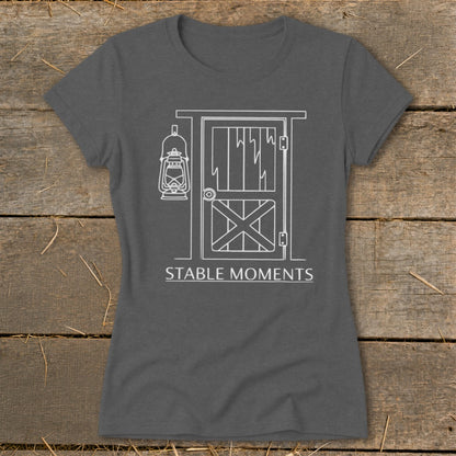 Dark grey t-shirt with white line art of a barn door, hanging lantern, and text "STABLE MOMENTS".