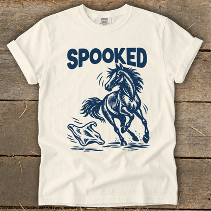 White t-shirt with navy graphic of a startled horse running from a ghost, text reads "SPOOKED".
