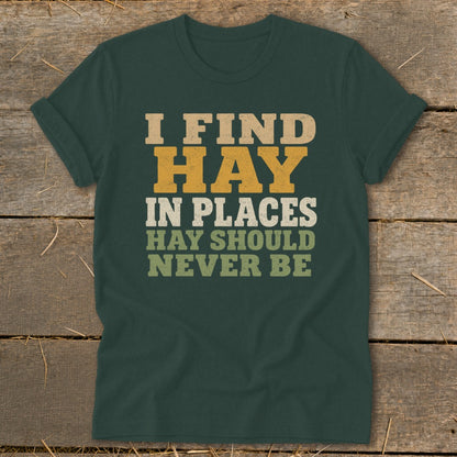 Dark green t-shirt with text "I FIND HAY IN PLACES HAY SHOULD NEVER BE".