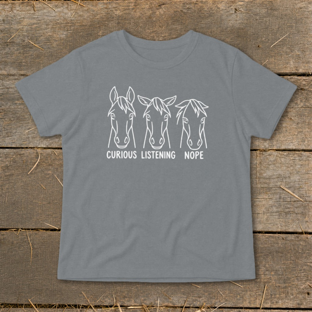 A grey t-shirt featuring a white graphic of three horse heads with the text "CURIOUS," "LISTENING," and "NOPE."