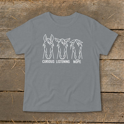 A grey t-shirt featuring a white graphic of three horse heads with the text "CURIOUS," "LISTENING," and "NOPE."